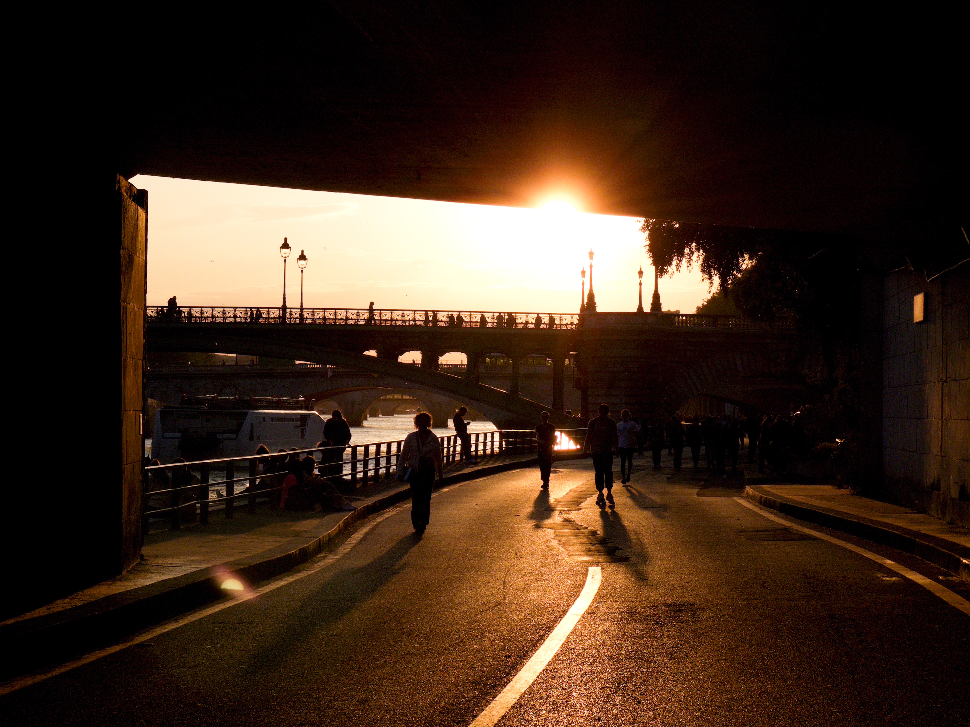 People walking under a bridge with a sunset in the background, Paris. People walking under a bridge with a sunset in the background, Paris.